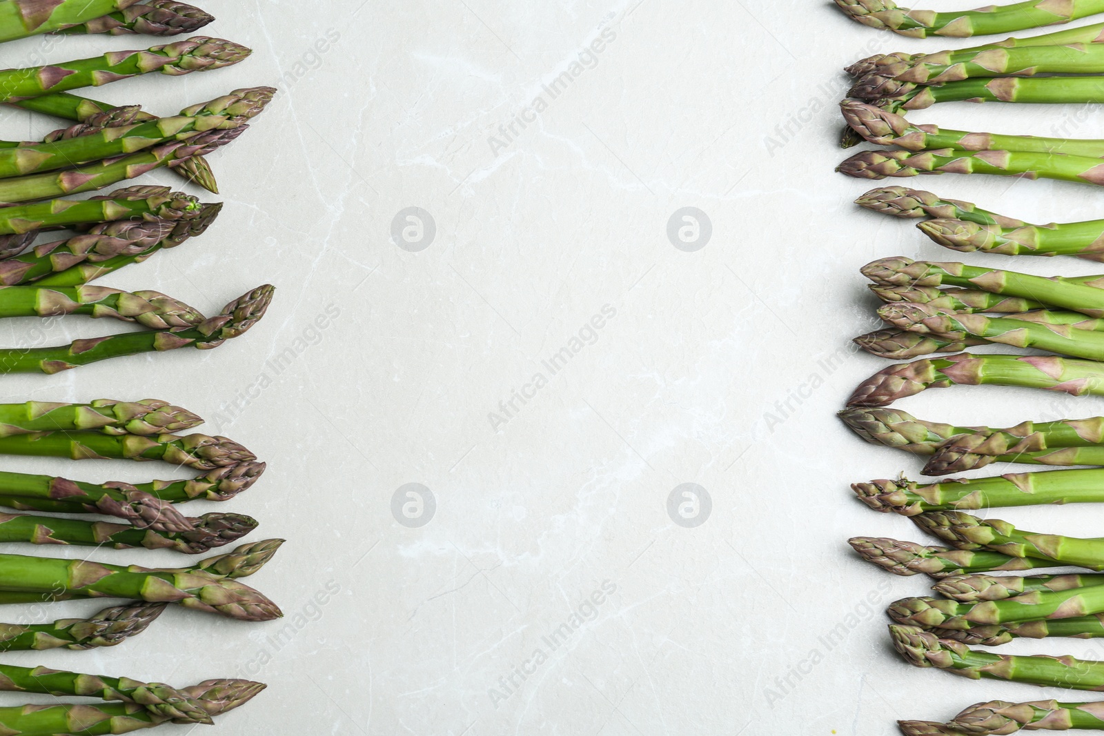 Photo of Fresh raw asparagus on light grey marble table, flat lay. Space for text