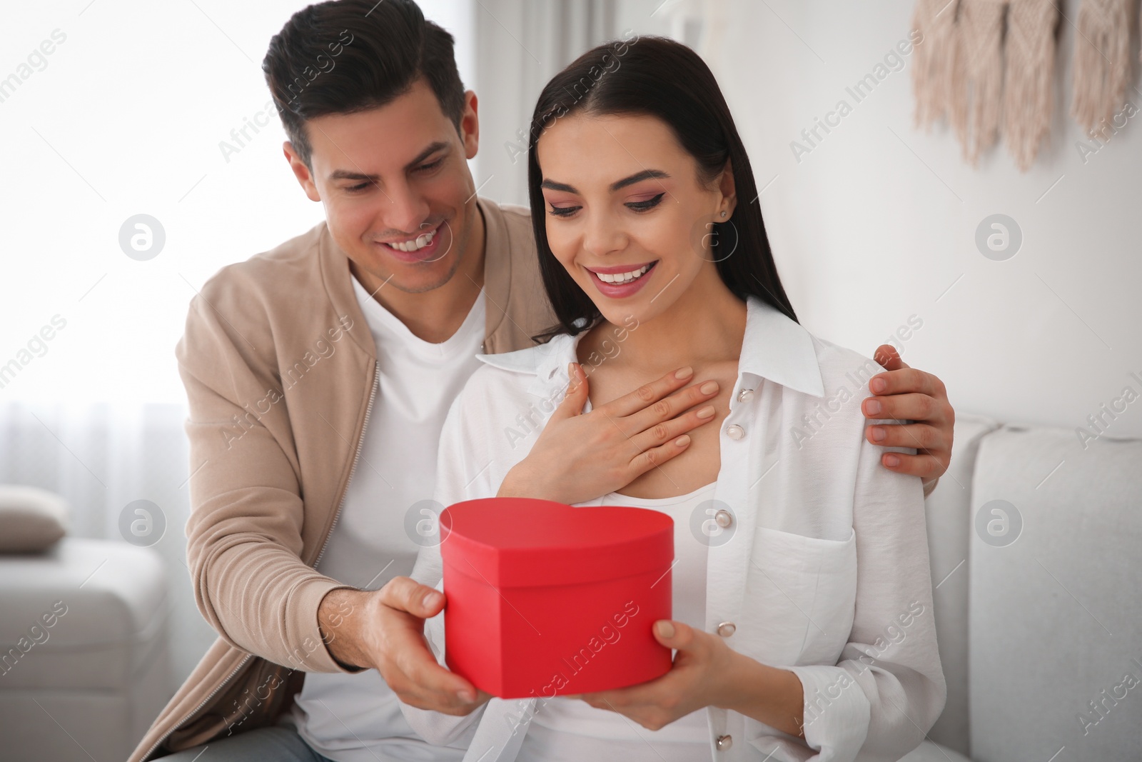 Photo of Man presenting gift to his beloved woman at home. Valentine's day celebration