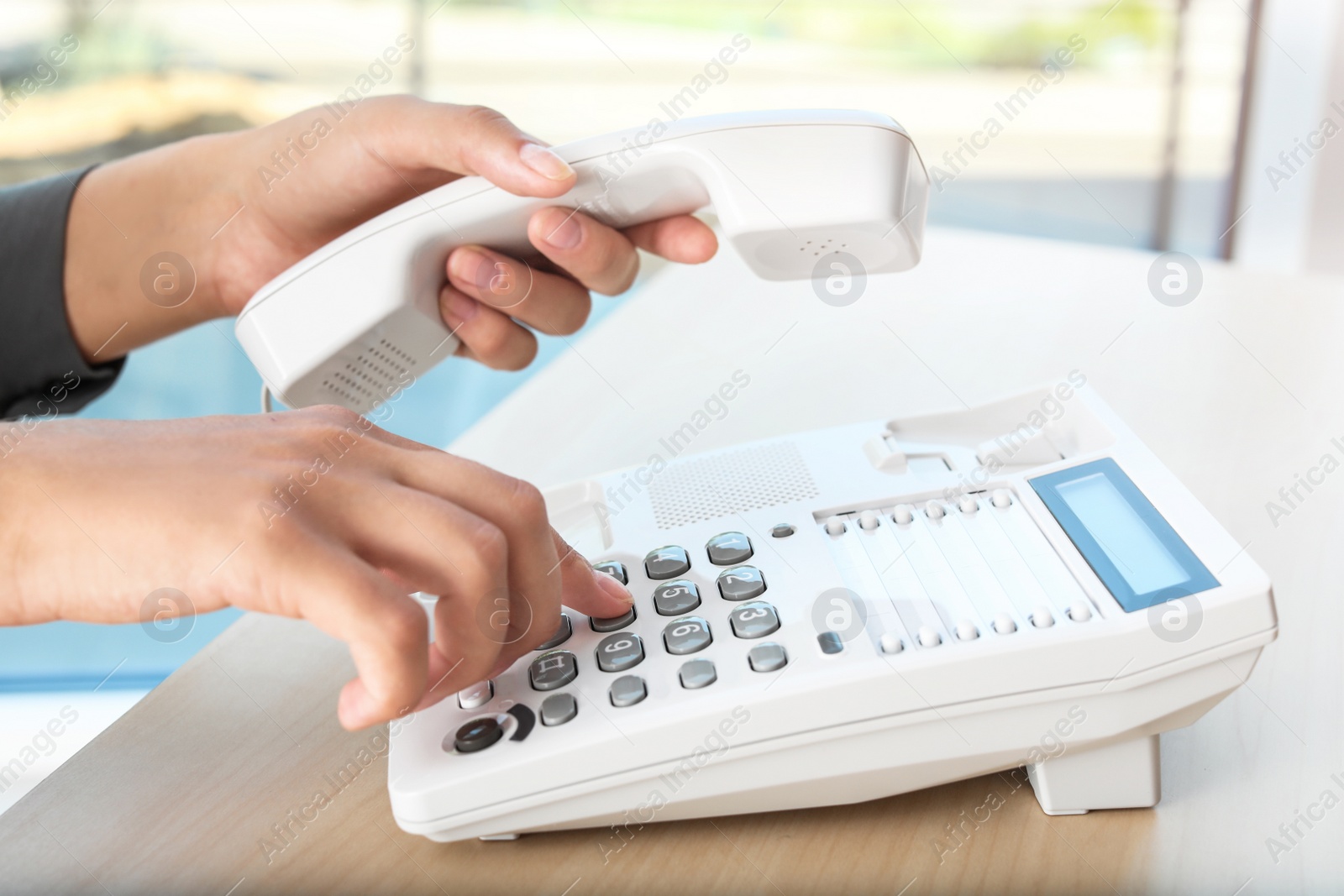 Photo of Woman dialing number on telephone at table in office