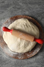 Photo of Raw dough and rolling pin on grey table, top view