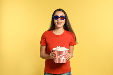 Woman with 3D glasses and popcorn during cinema show on color background