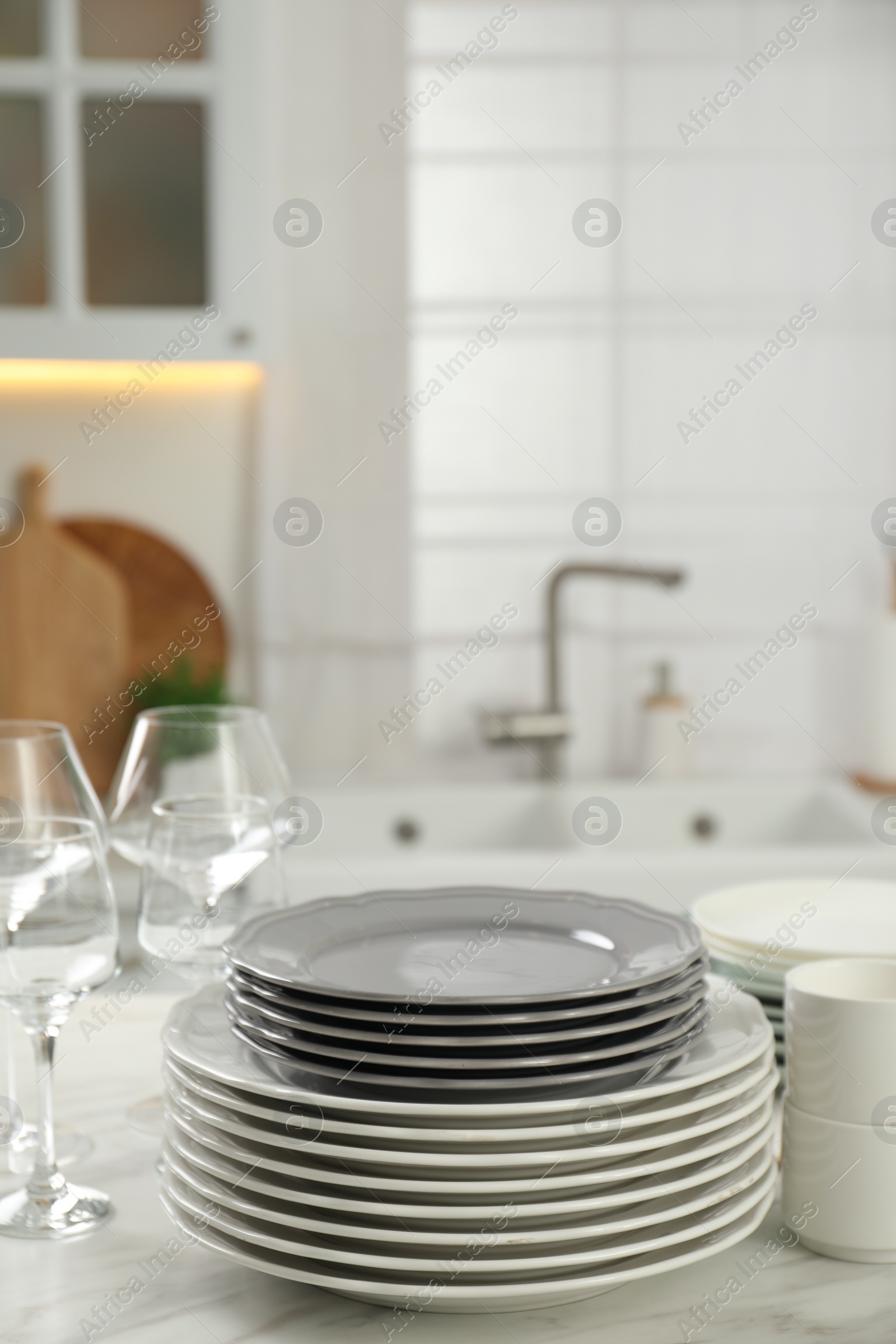 Photo of Clean plates and glasses on white marble table in kitchen