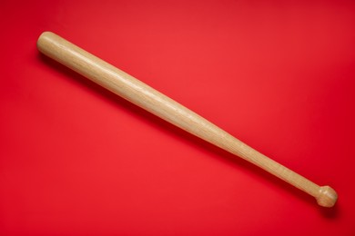 Photo of Wooden baseball bat on red background, top view. Sports equipment