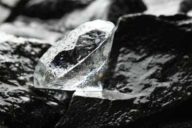 Photo of Beautiful shiny diamond on wet coal, closeup