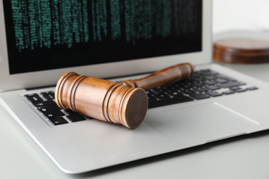 Photo of Modern laptop and wooden gavel on table, closeup. Cyber crime