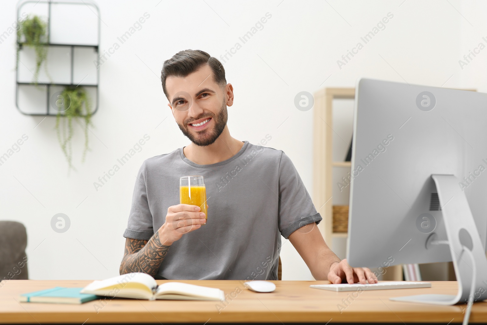 Photo of Handsome man with delicious smoothie at workplace in office