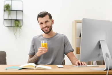 Photo of Handsome man with delicious smoothie at workplace in office
