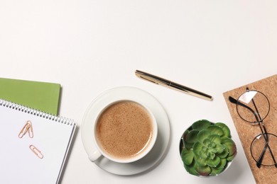 Cup of drink, glasses and different stationery on white desk, flat lay with space for text. Home office