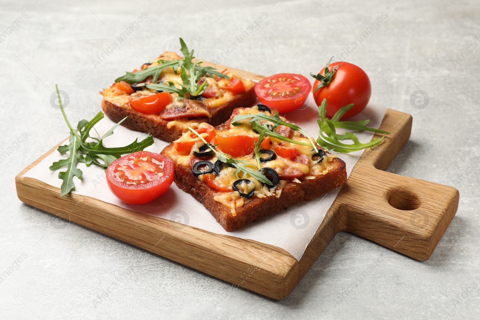 Photo of Tasty pizza toasts, fresh tomatoes and parsley on grey table