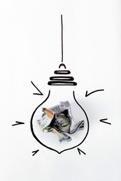 Photo of Composition with crumpled banknote and drawing of lamp bulb on white background, top view. Creative concept