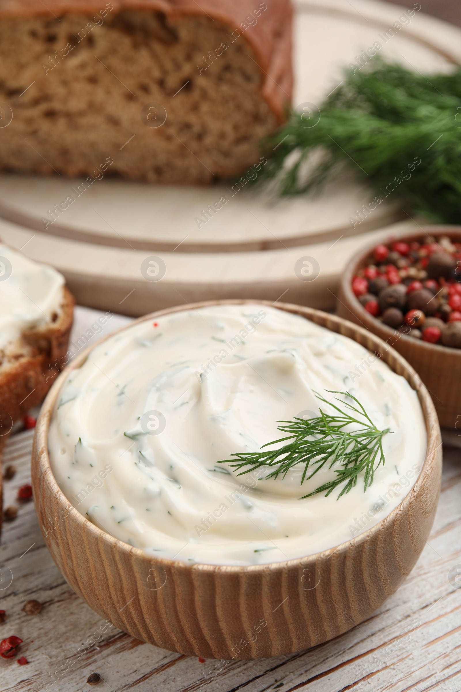 Photo of Tasty creamy dill sauce in bowl on white wooden table