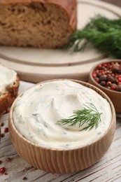 Photo of Tasty creamy dill sauce in bowl on white wooden table