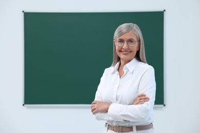 Photo of Portrait of happy professor near blackboard in classroom, space for text