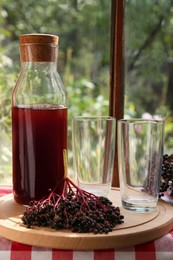 Photo of Elderberry drink and Sambucus berries on table near window