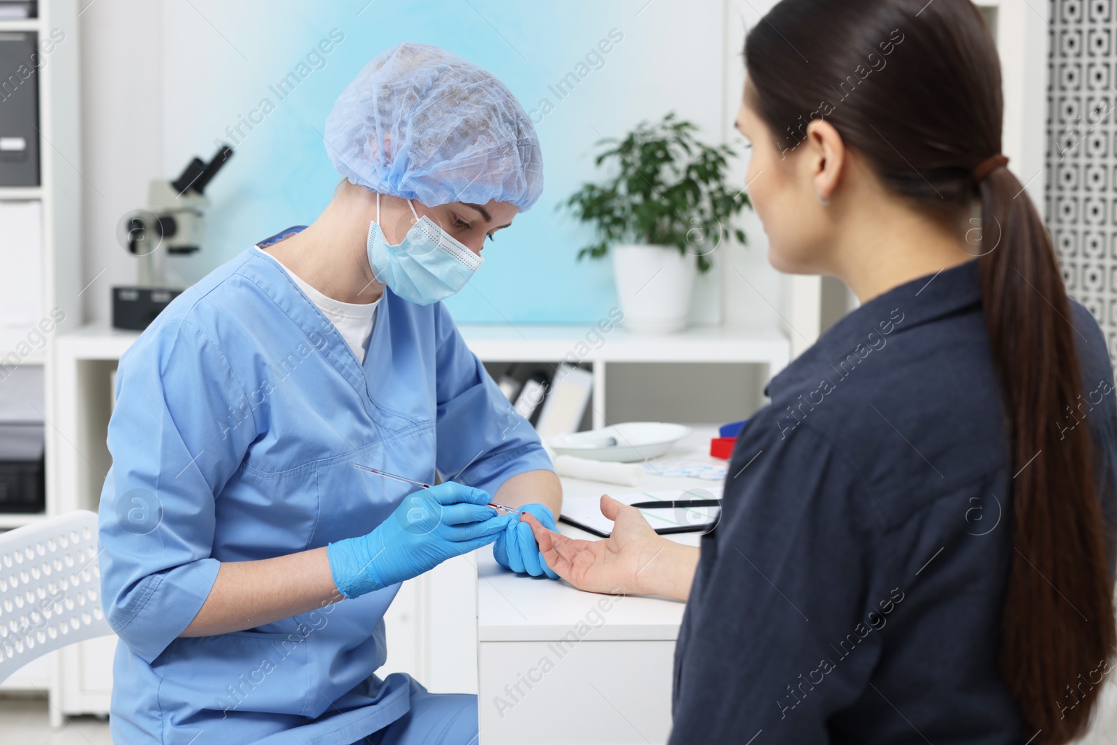 Photo of Laboratory testing. Doctor taking blood sample from patient at white table in hospital