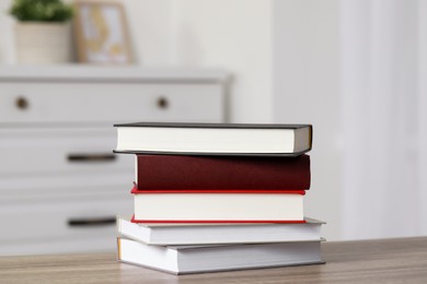 Photo of Stack of hardcover books on wooden table indoors