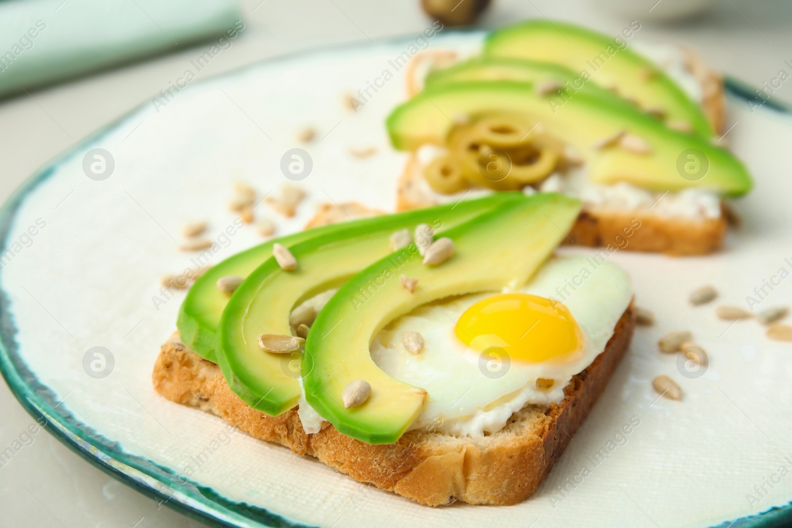 Photo of Crisp toast with avocado and quail egg on plate, closeup