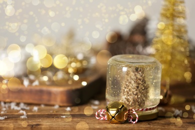 Image of Handmade snow globe and Christmas decorations on wooden table, space for text. Bokeh effect