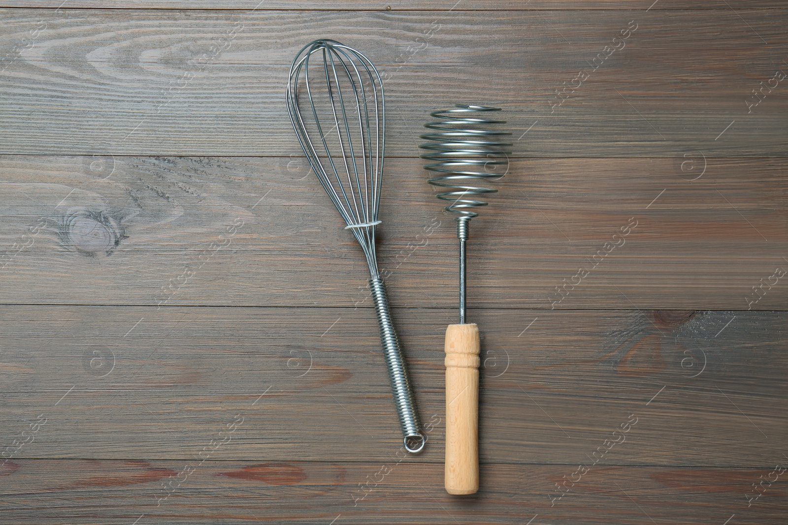 Photo of Two metal whisks on wooden table, top view