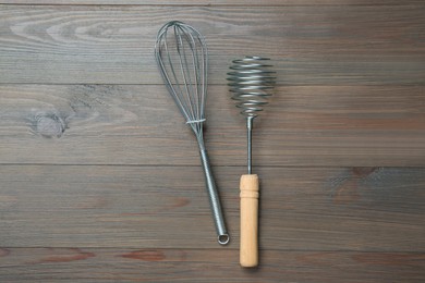 Photo of Two metal whisks on wooden table, top view