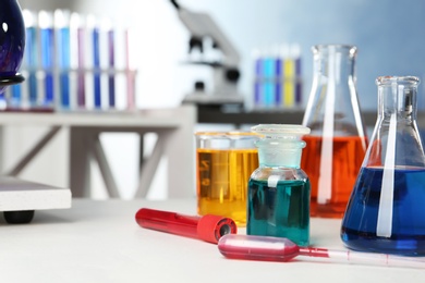 Photo of Different glassware with samples on table in chemistry laboratory