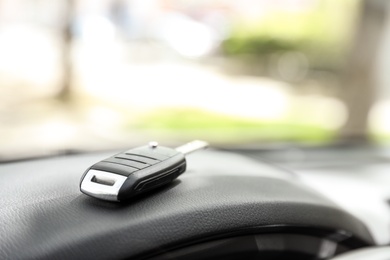 Photo of Car key on dashboard in auto against blurred background, space for text
