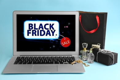 Photo of Laptop with Black Friday announcement, gifts and accessories on light blue background