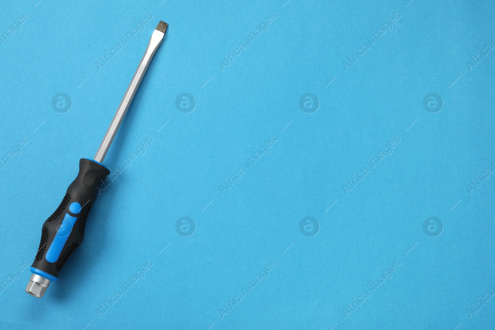 Photo of Screwdriver with black handle on blue background, top view. Space for text