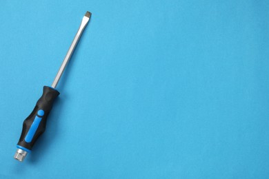 Photo of Screwdriver with black handle on blue background, top view. Space for text