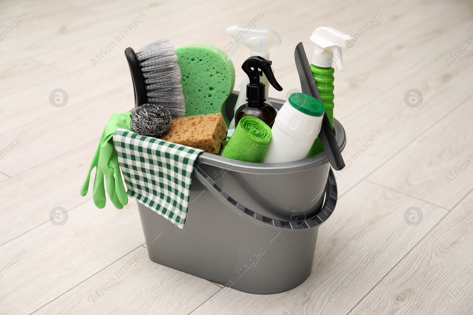 Photo of Different cleaning supplies in bucket on floor at home