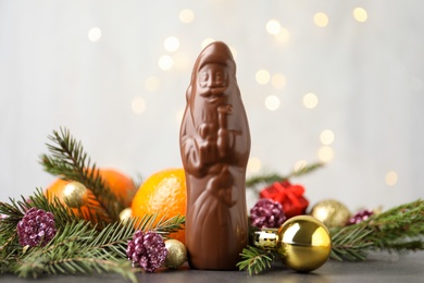 Composition with chocolate Santa Claus, tangerine fruits and Christmas decorations on light grey background