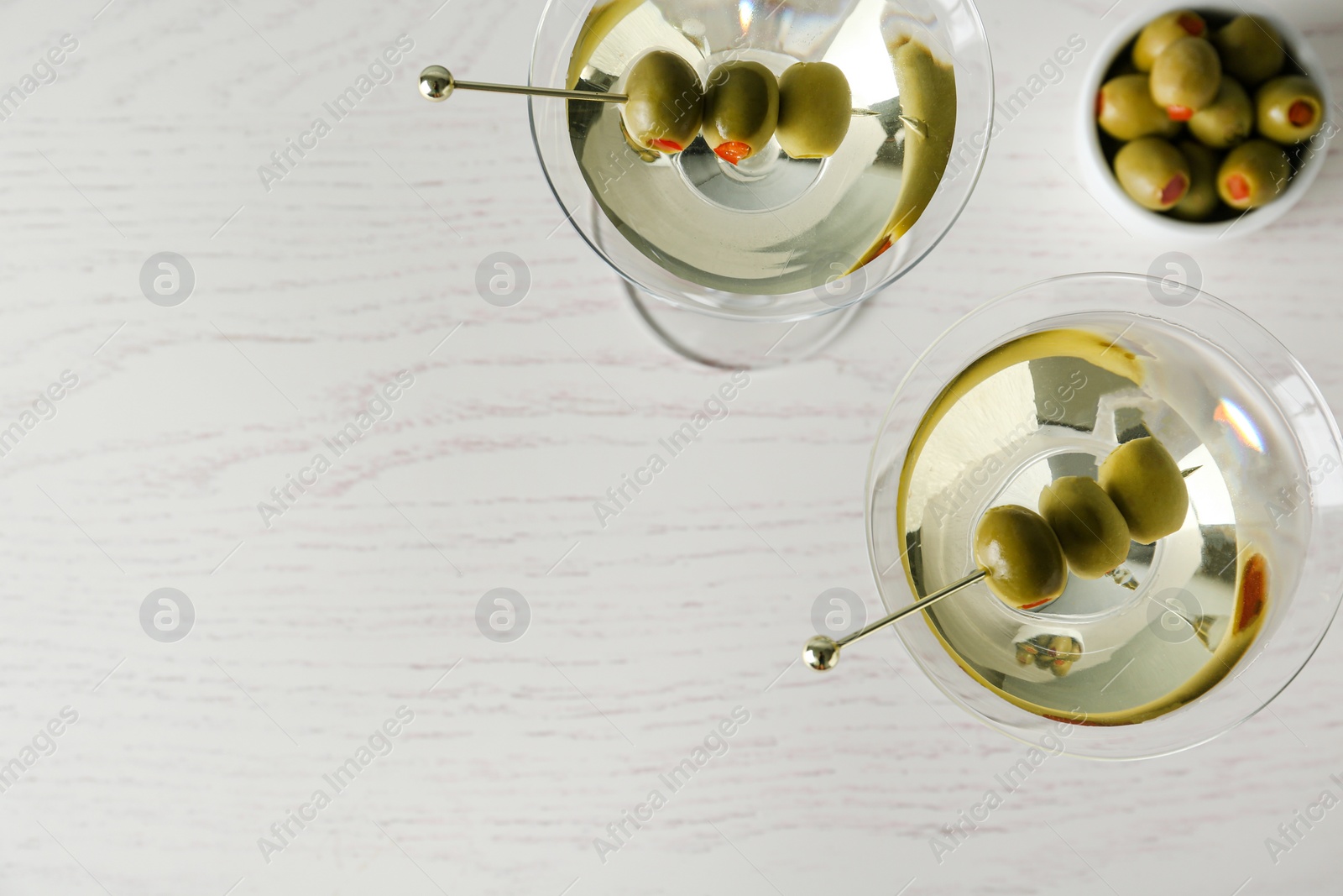 Photo of Glasses of Classic Dry Martini with olives on wooden table, flat lay. Space for text