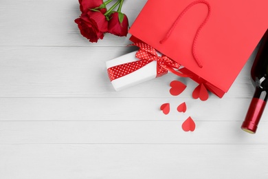 Photo of Flat lay composition with gift box and roses on white wooden background, space for text. Valentine's Day celebration
