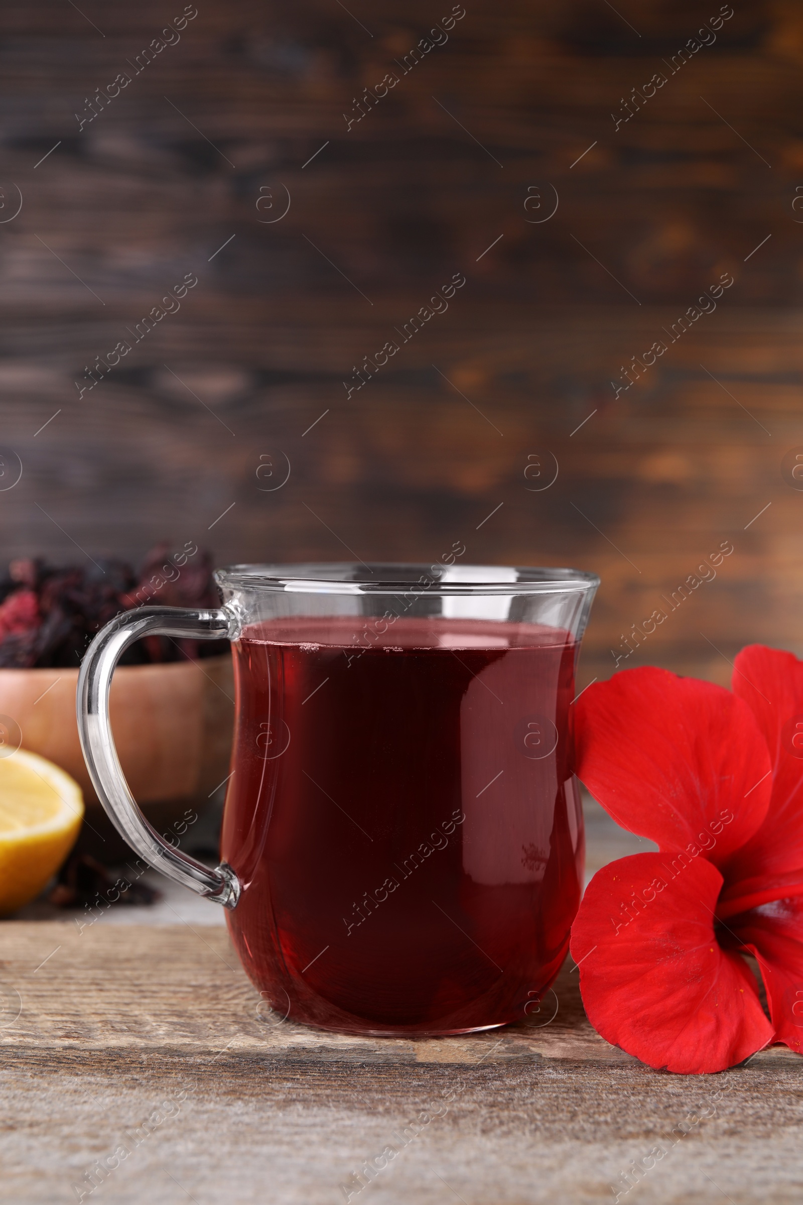 Photo of Delicious hibiscus tea and beautiful flower on wooden table. Space for text