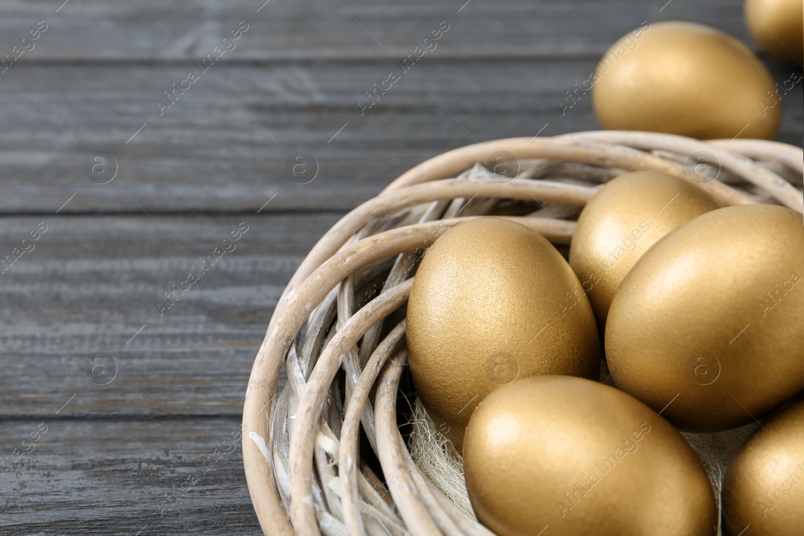 Photo of Golden eggs in nest on wooden background, closeup