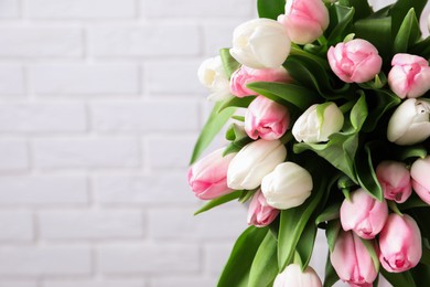 Photo of Beautiful bouquet of tulips against white brick wall. Space for text