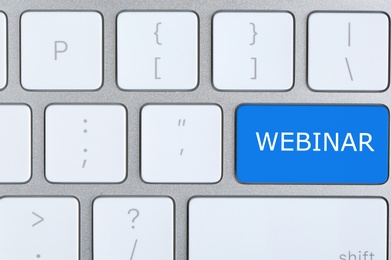 Image of Online learning. Blue button with word Webinar on computer keyboard, top view