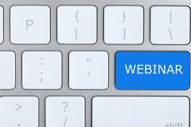 Online learning. Blue button with word Webinar on computer keyboard, top view