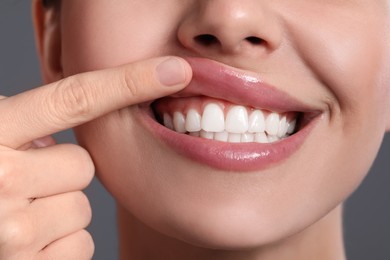 Photo of Young woman showing healthy gums on grey background, closeup