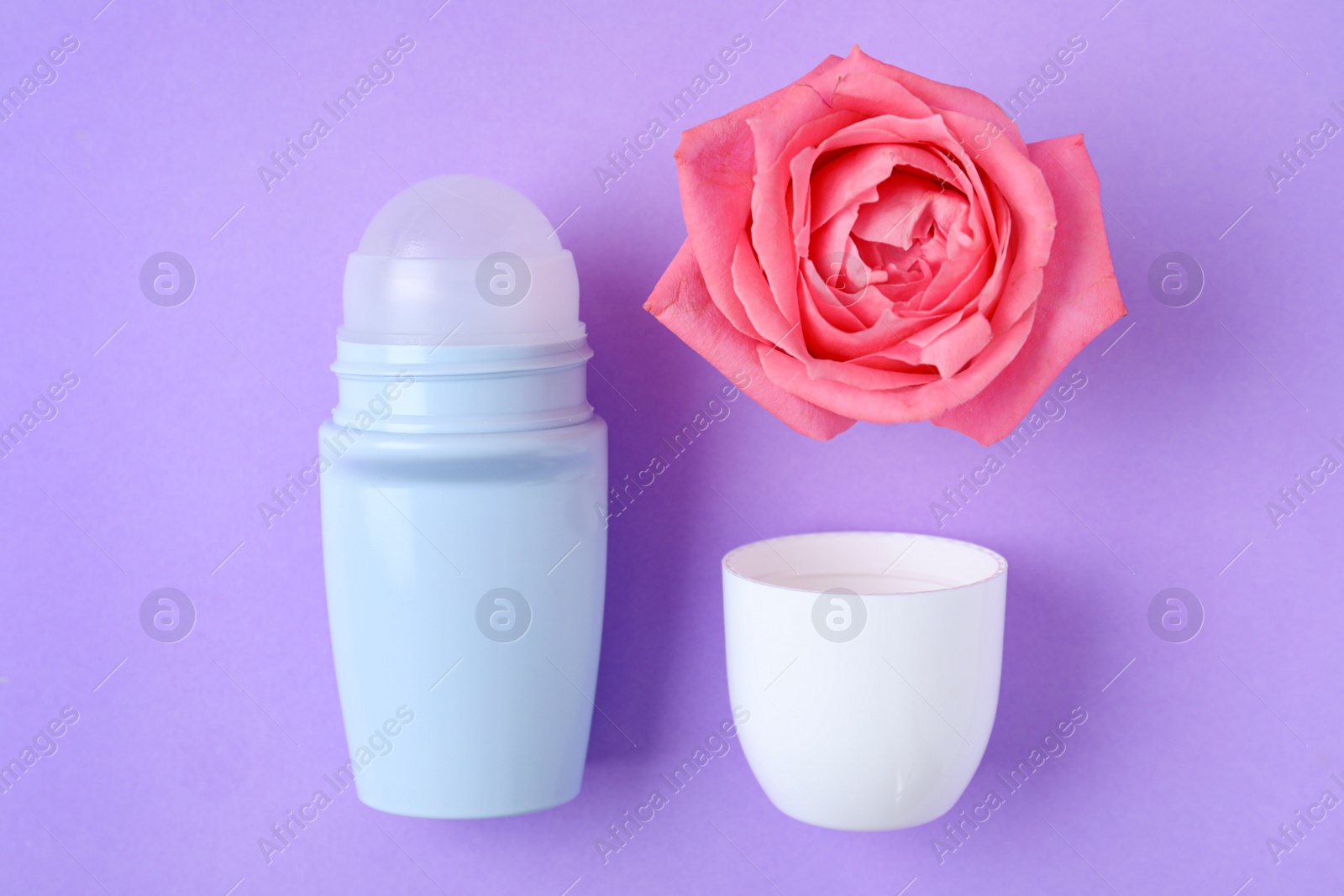 Photo of Flat lay composition with natural female roll-on deodorant on purple background