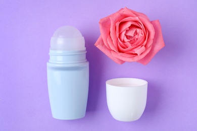 Photo of Flat lay composition with natural female roll-on deodorant on purple background