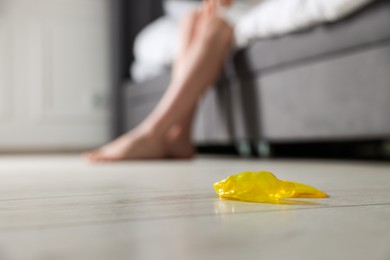 Woman sitting on bed and unrolled condom indoors, closeup with space for text. Safe sex