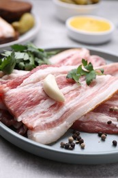 Photo of Slices of tasty pork fatback with spices on grey table, closeup