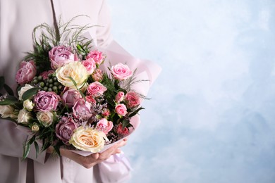 Photo of Woman with bouquet of beautiful roses on light blue background, closeup. Space for text