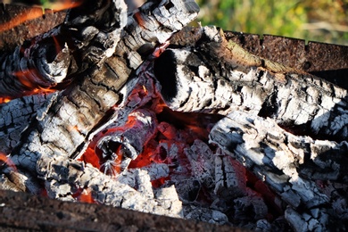 Photo of Metal brazier with burning wood outdoors, closeup
