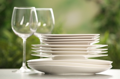 Photo of Set of clean dishware and wineglasses on grey table against blurred background