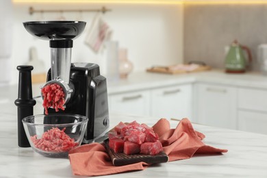 Photo of Electric meat grinder with beef mince on white table in kitchen, space for text