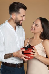 Lovely couple with gift on beige background