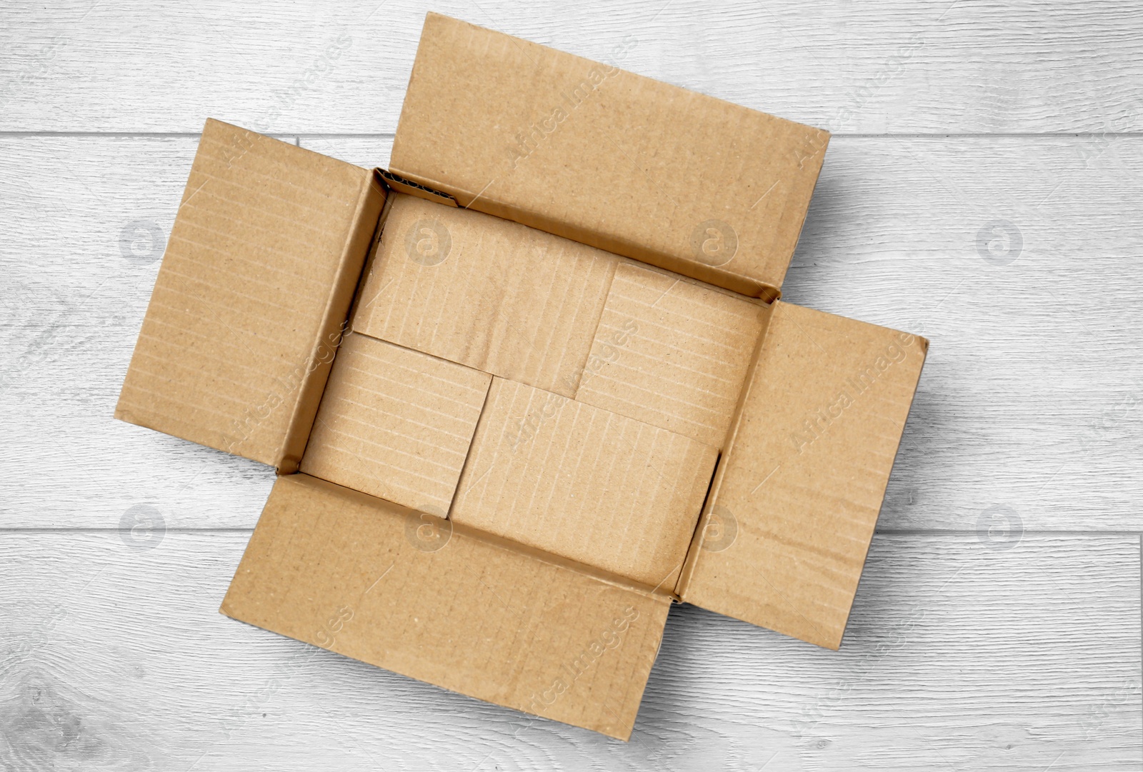 Photo of Open empty cardboard box on wooden floor