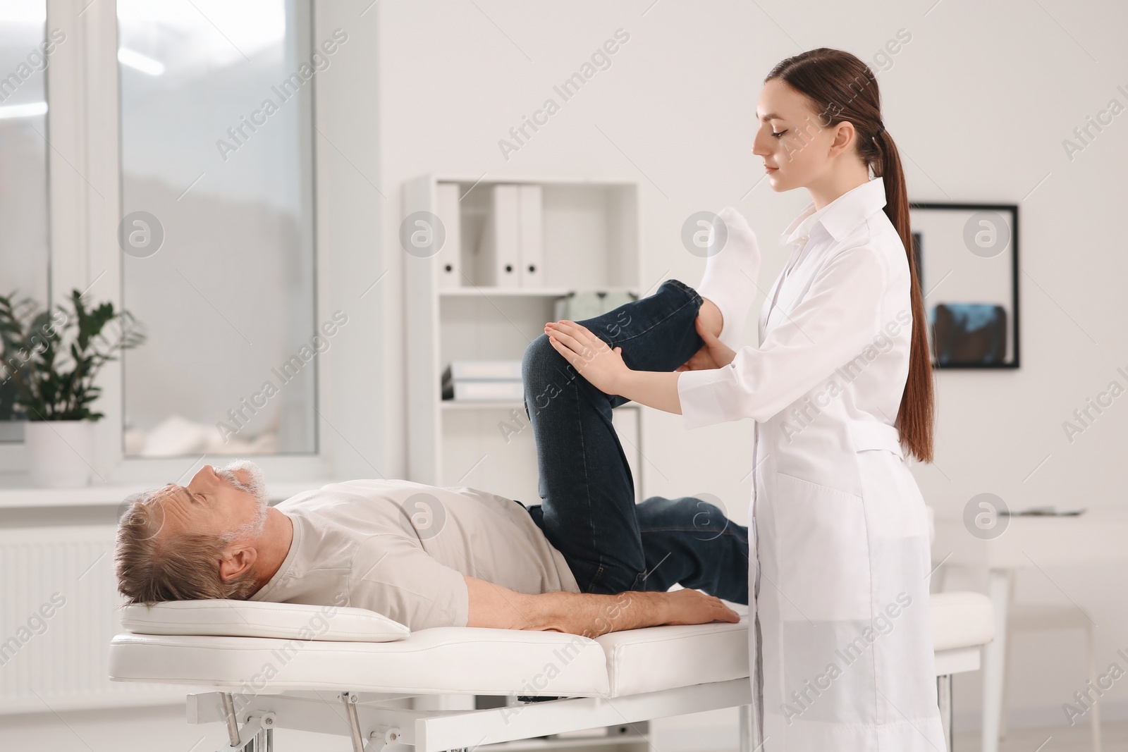 Photo of Professional orthopedist examining patient's leg in clinic